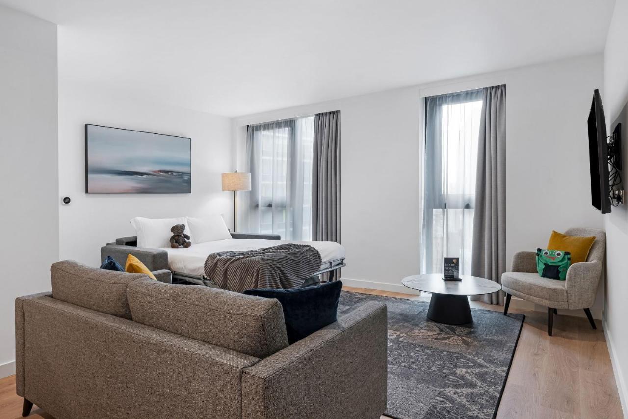Citysuites 2 Aparthotel Manchester Exteriör bild The photo shows a modern living space that incorporates a cozy and inviting atmosphere. It features a light-colored couch with colorful cushions, positioned in front of a coffee table. There's a comfortable armchair nearby, and a throw blanket is dra