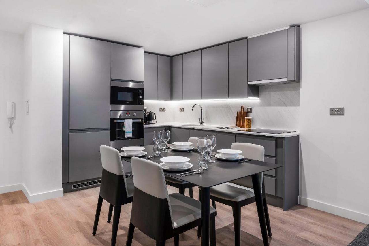 Citysuites 2 Aparthotel Manchester Exteriör bild The photo shows a modern kitchen and dining area. The kitchen features sleek, gray cabinetry and a countertop that complements the overall aesthetic. There are built-in appliances, including an oven and refrigerator, arranged neatly. Next to the kitc