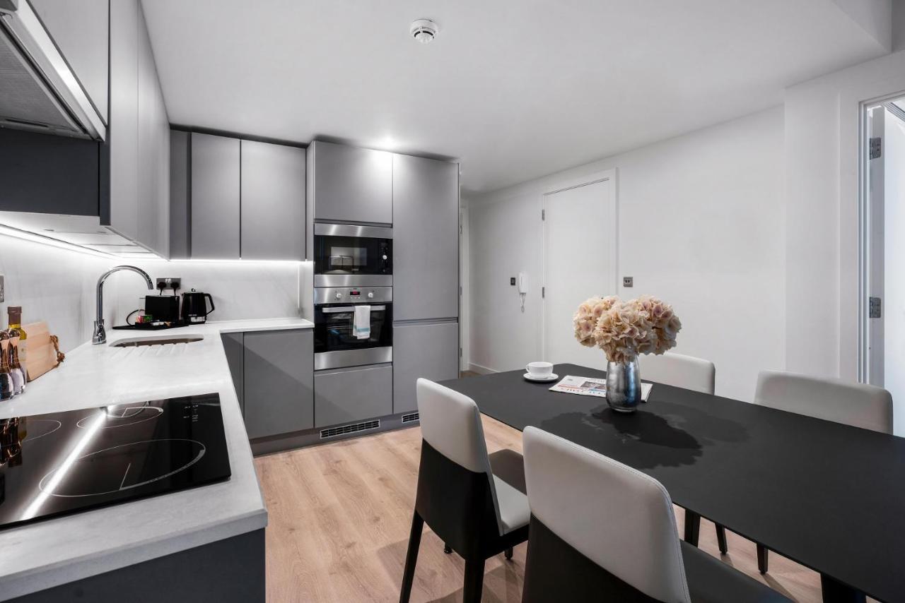 Citysuites 2 Aparthotel Manchester Exteriör bild The photo shows a modern kitchen and dining area. The kitchen features sleek gray cabinets, a countertop with an embedded cooktop, and built-in appliances, including an oven and microwave. There’s a small coffee maker on the counter. Adjacent to the 