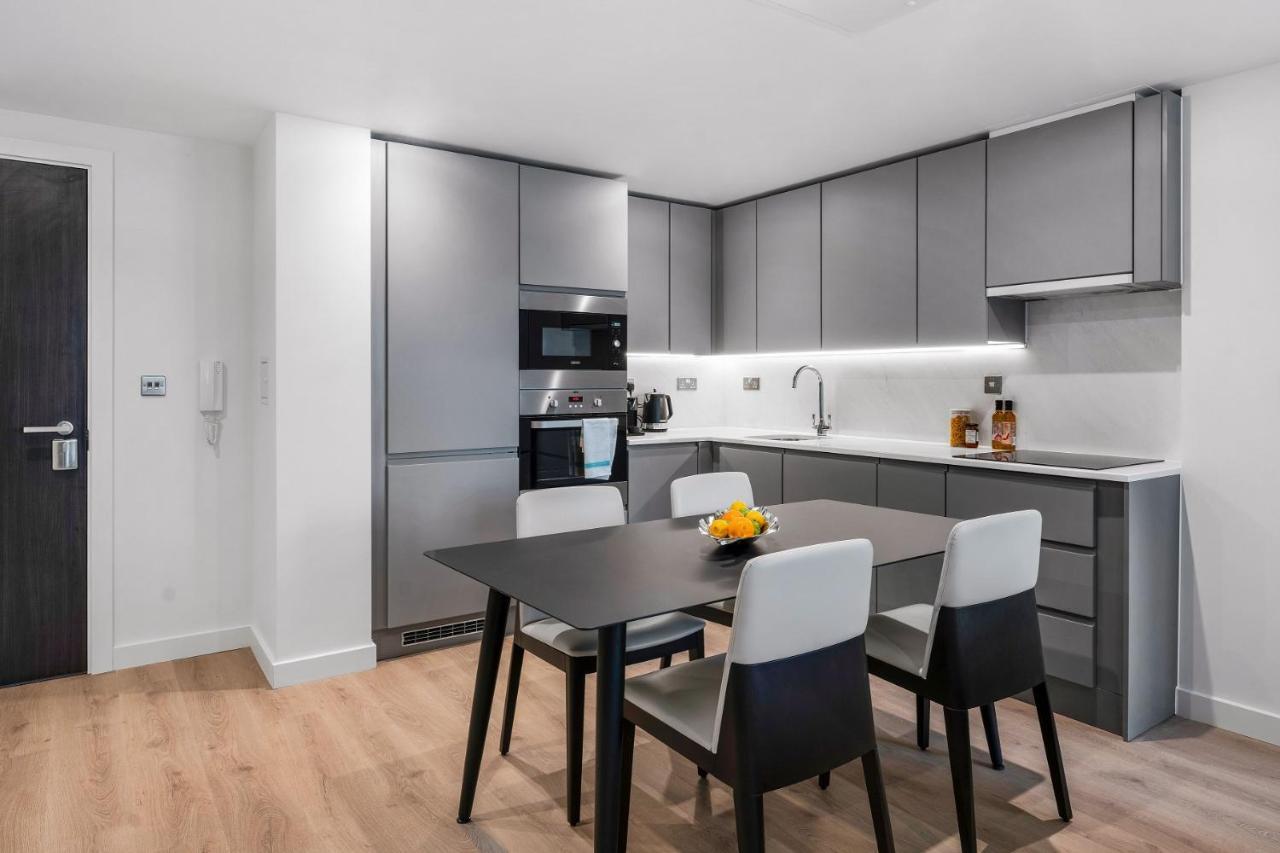 Citysuites 2 Aparthotel Manchester Exteriör bild The photo shows a modern kitchen with a sleek and minimalist design. The cabinetry features a gray finish, and there are built-in appliances, including an oven and possibly a microwave. The countertop is light-colored, providing contrast to the darke