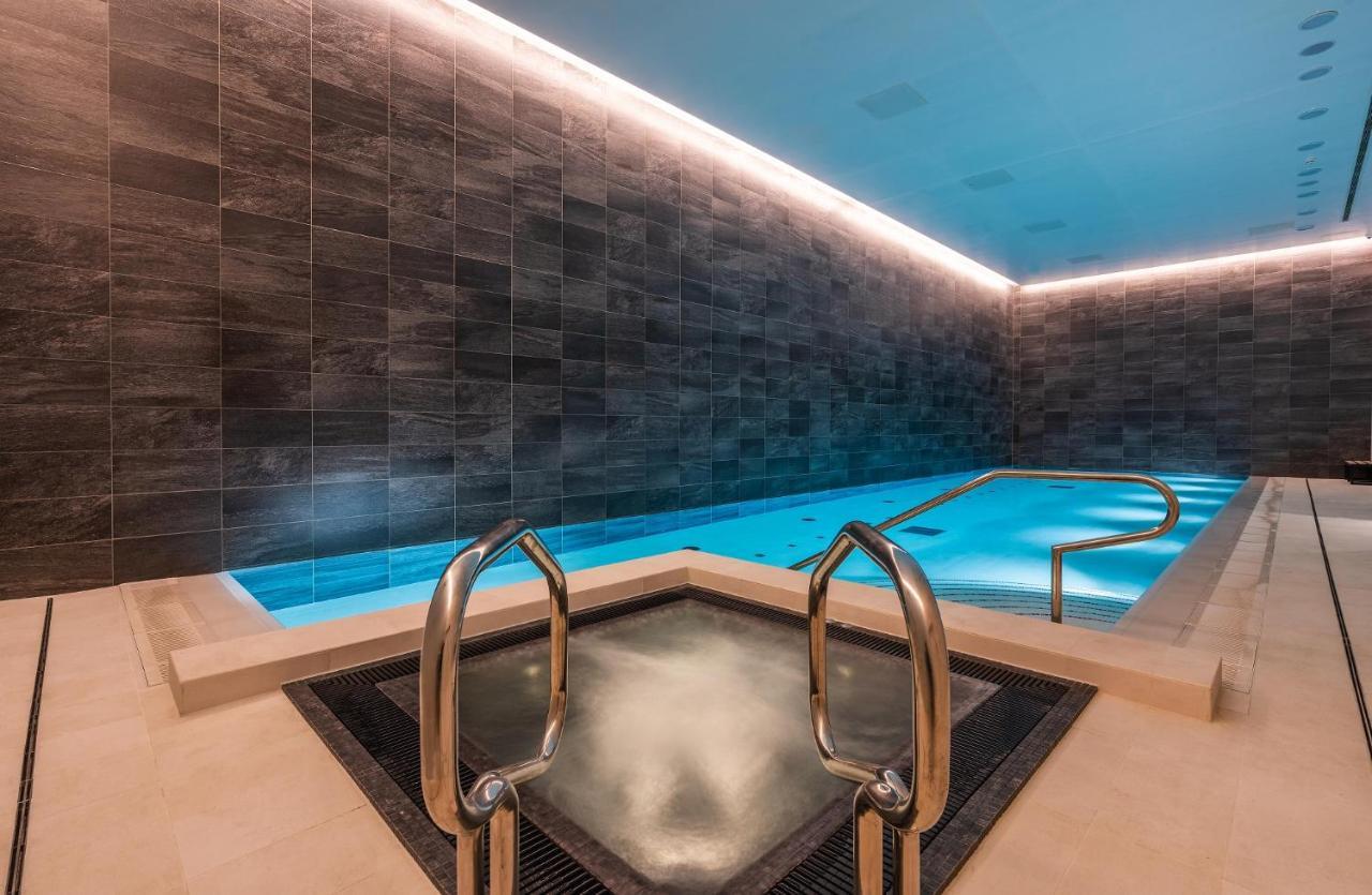 Citysuites 2 Aparthotel Manchester Exteriör bild The photo shows a modern indoor swimming pool area. The pool features a sleek, rectangular design with a beautiful blue water that seems illuminated. Surrounding the pool are dark, textured walls, adding to the elegant atmosphere. There are dual meta